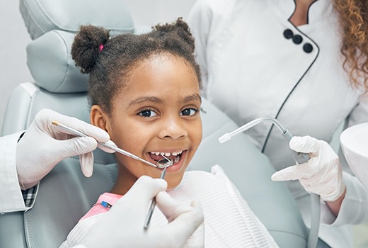 Girl with curly brown hair in pigtails having dental checkup