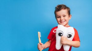 Child holding a toothbrush and tooth plushie